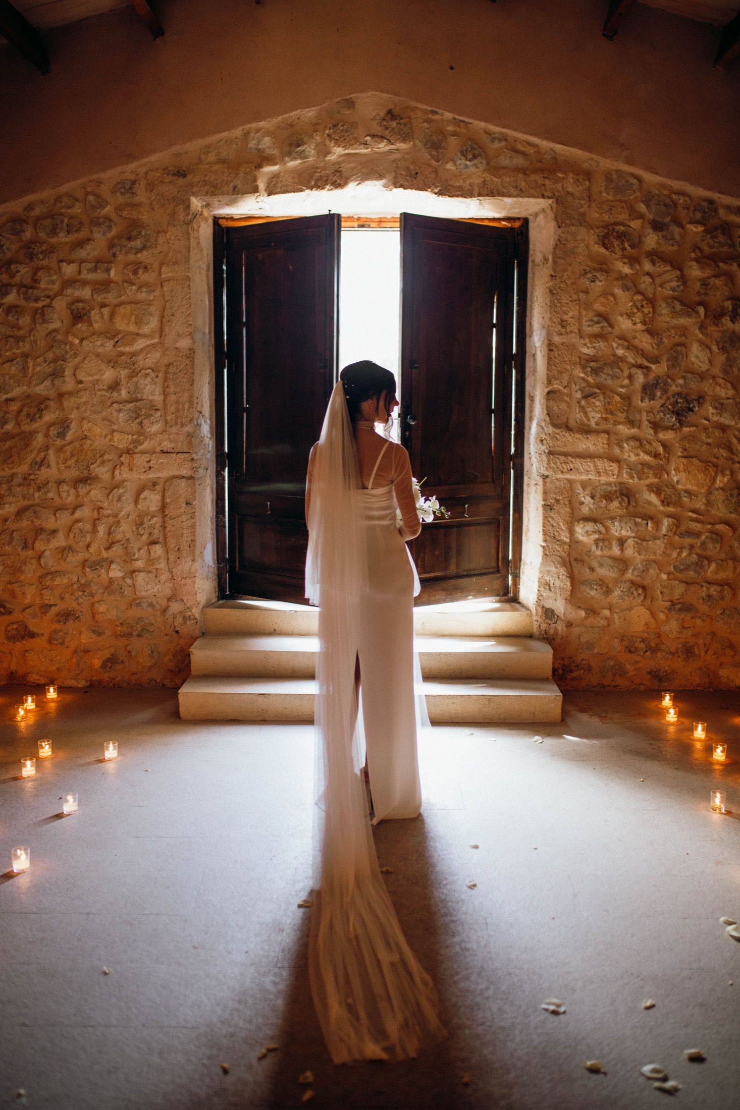 A sequence of photos showing a white wedding dress silhouetted against a rustic stone wall with candlelight and open windows.