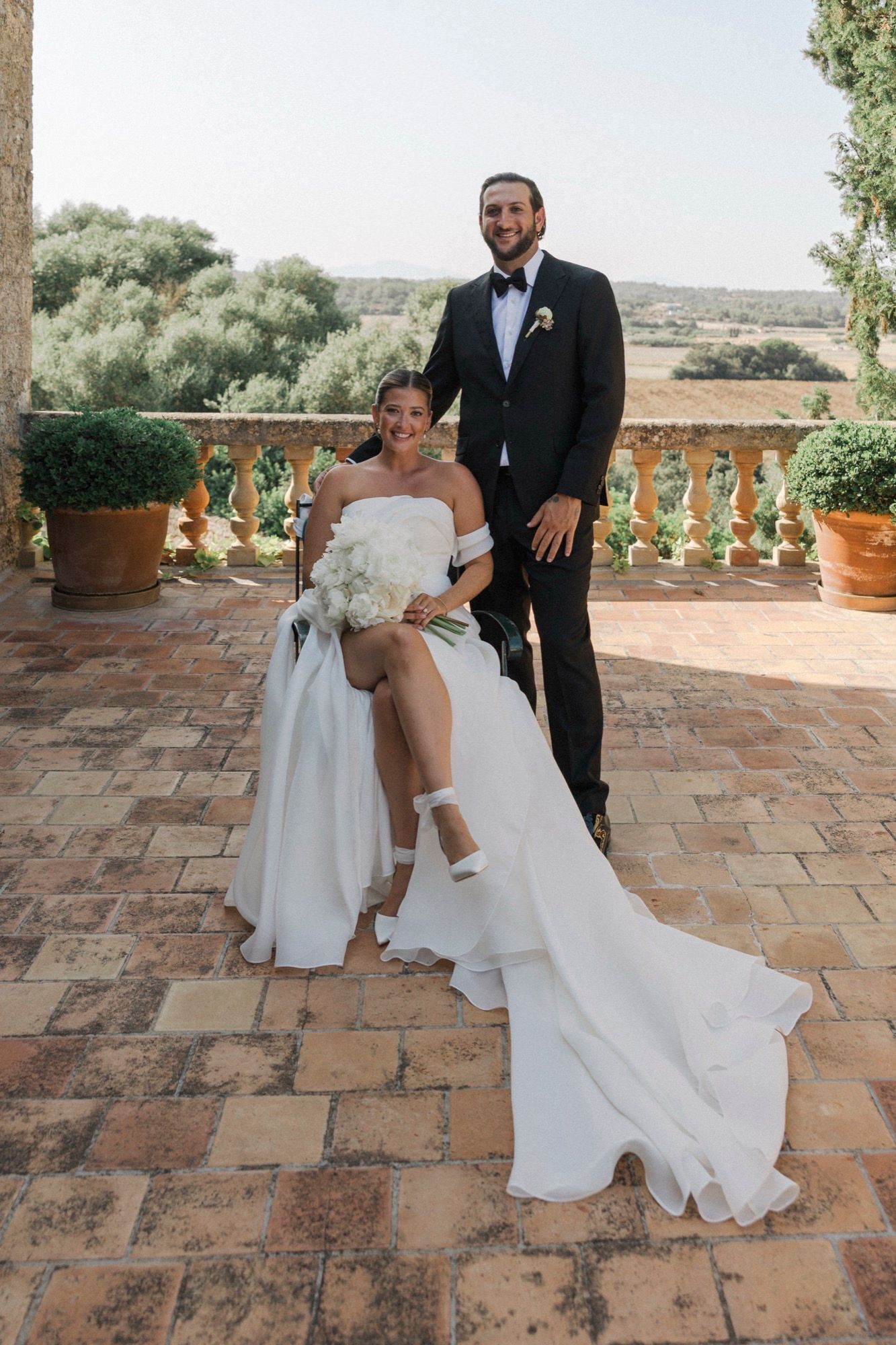 Newlyweds share playful moments on a rustic stone patio in Mallorca.