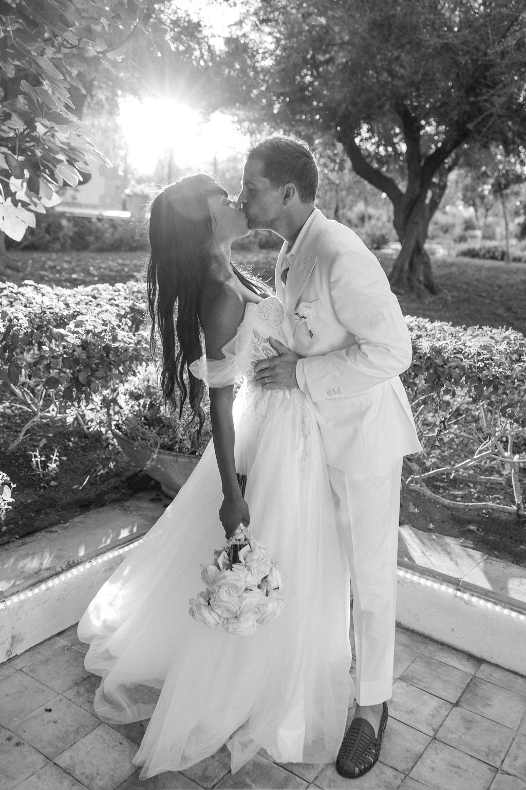 Black and white wedding photos capturing romantic moments in a garden setting.