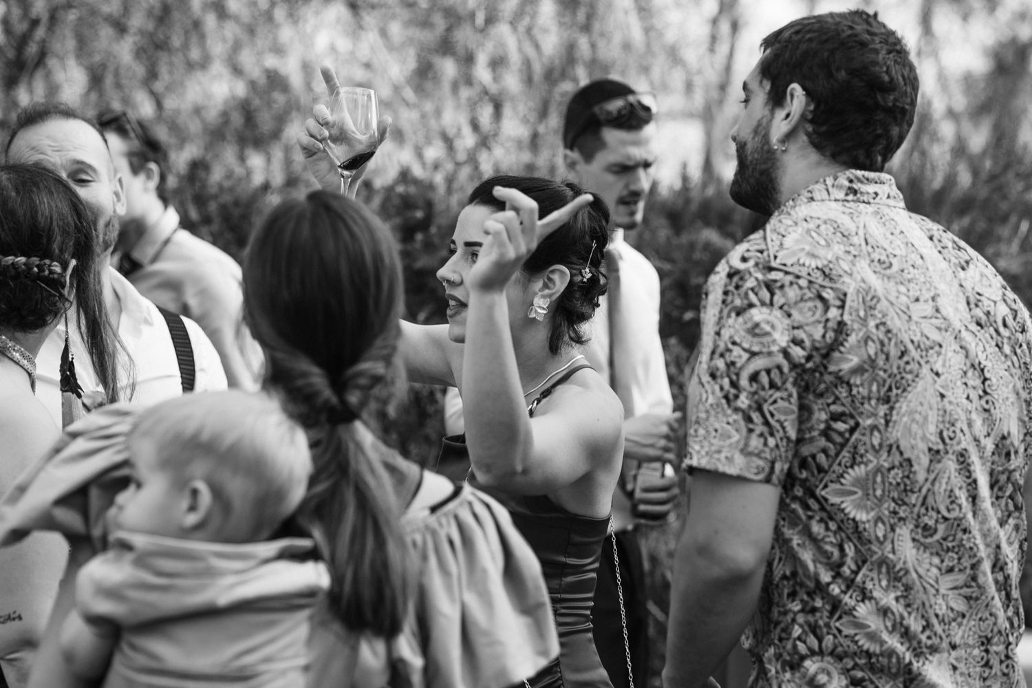 Black and white photo showing people dancing and celebrating at what appears to be a lively wedding reception.