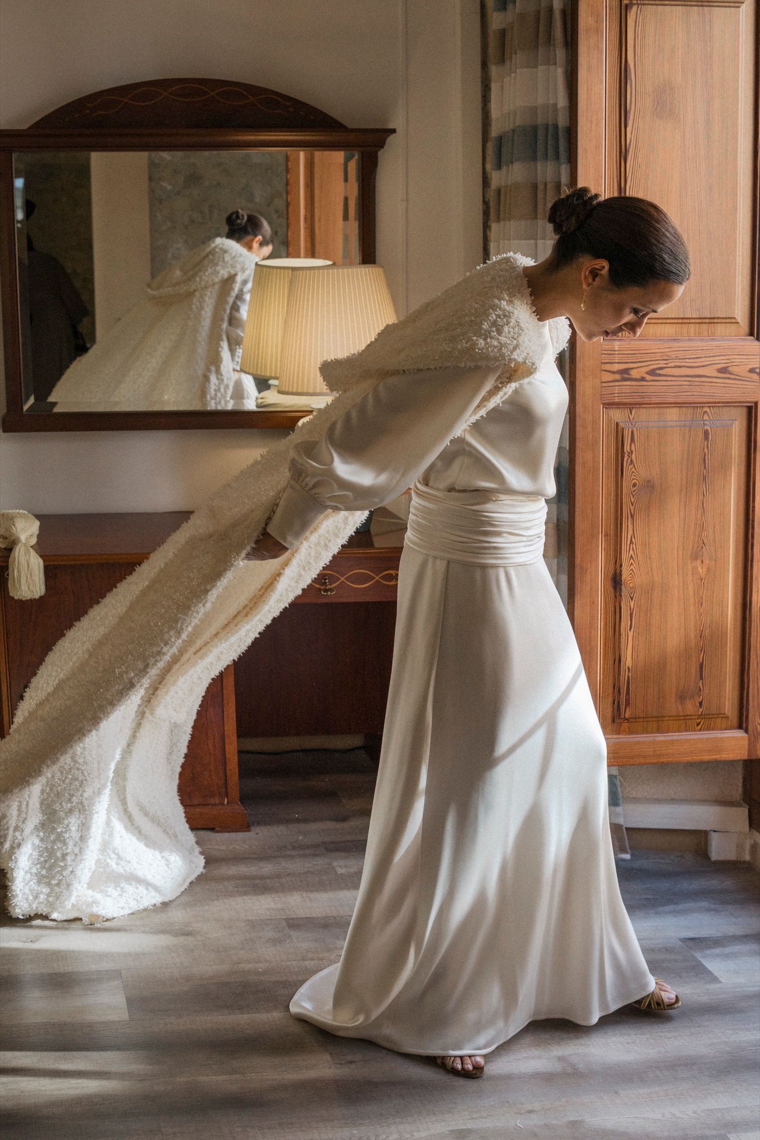 A white wedding dress flows elegantly as someone twirls in an indoor setting with wooden furniture.