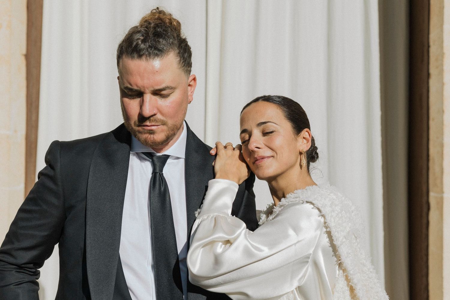 Intimate wedding portrait against white backdrop with elegant formal attire.