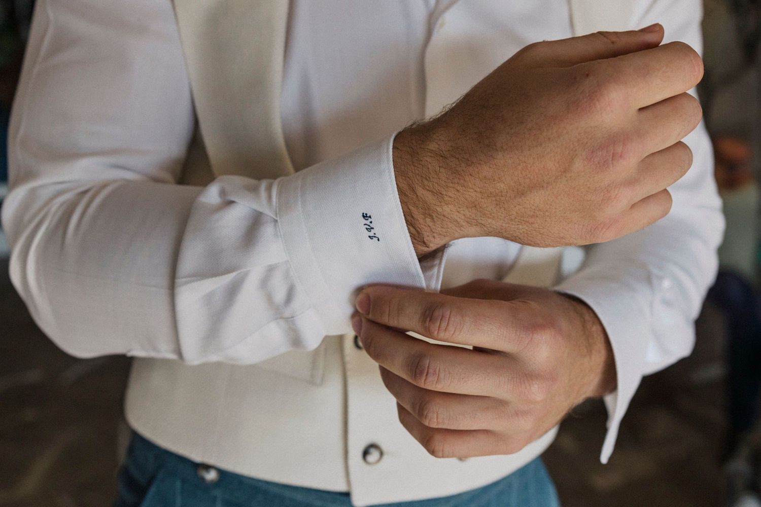 Close-up view of hands adjusting white dress shirt cuffs with elegant cufflinks.