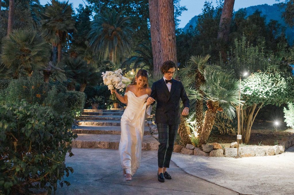 Outdoor evening wedding venue with illuminated trees and garden pathways.