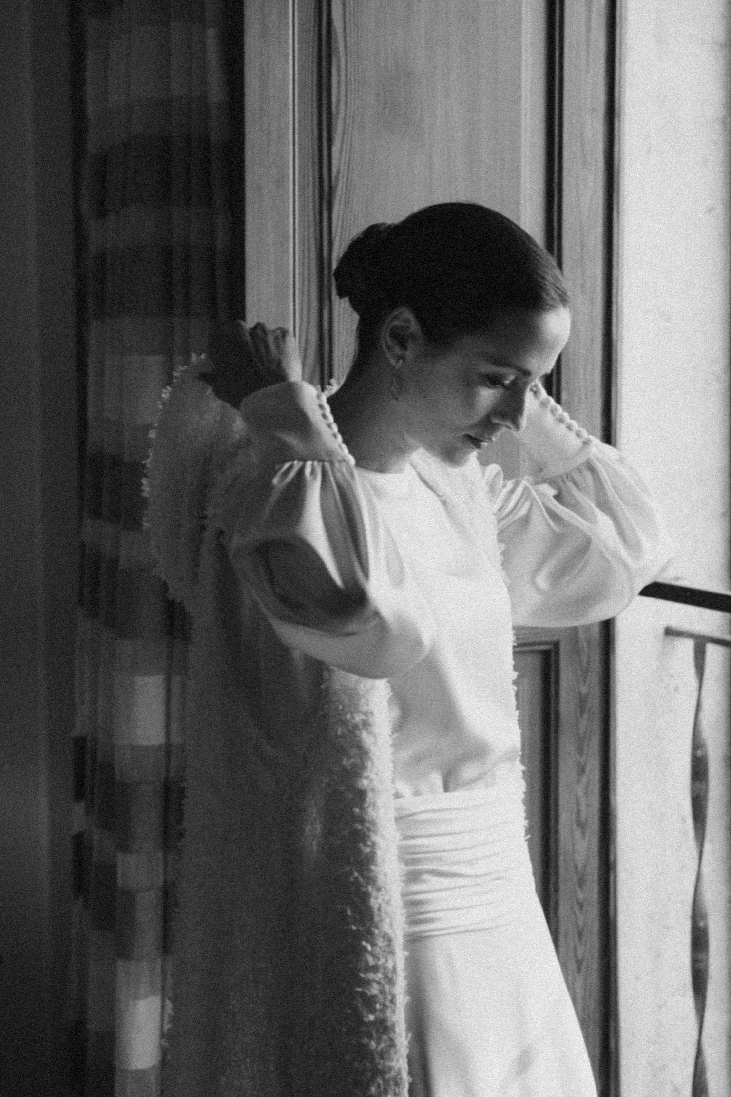 Figure in white clothing creating artistic movement against window light.