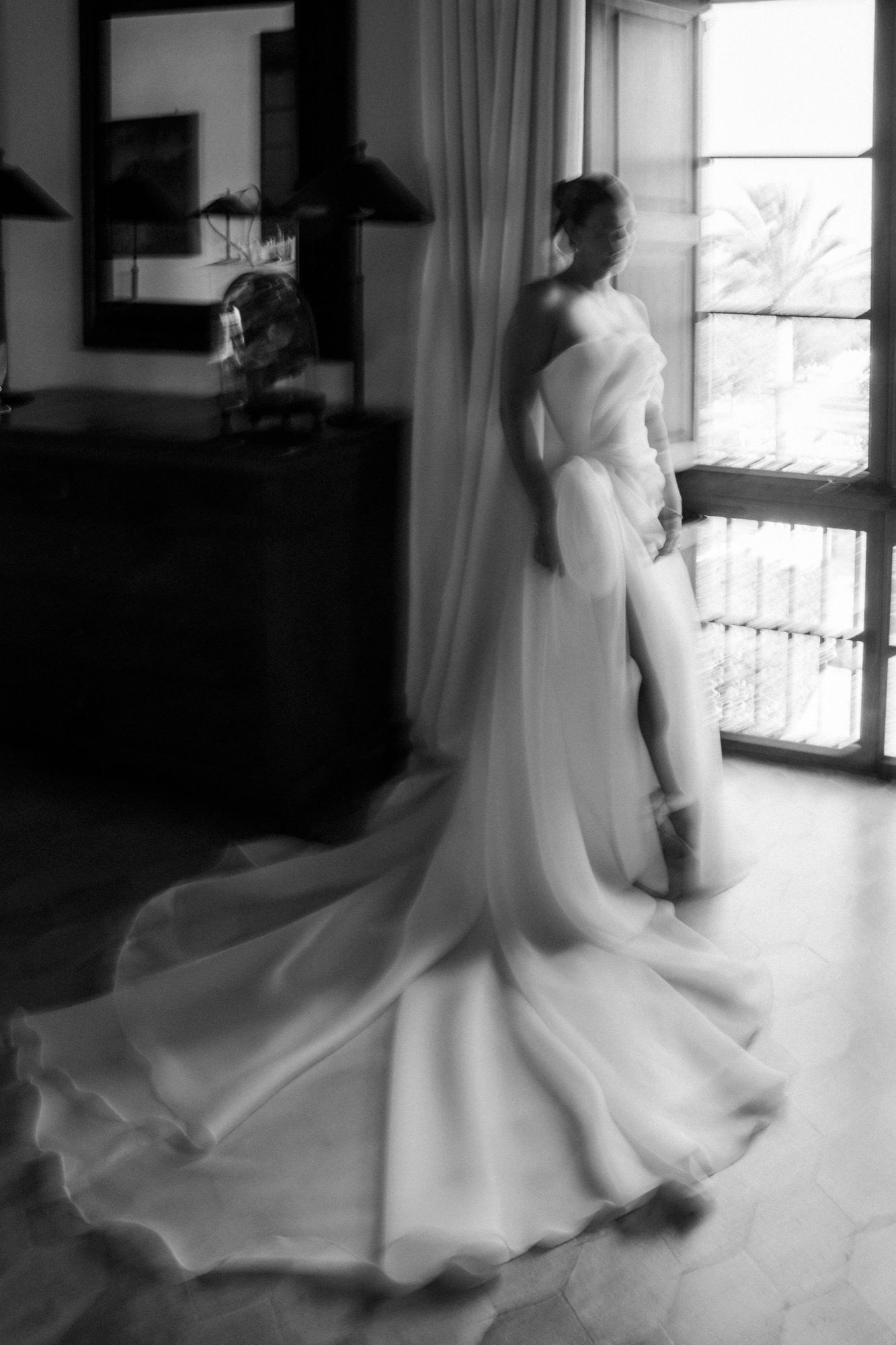 Elegant white wedding dress with flowing train captured in a bright interior space.
