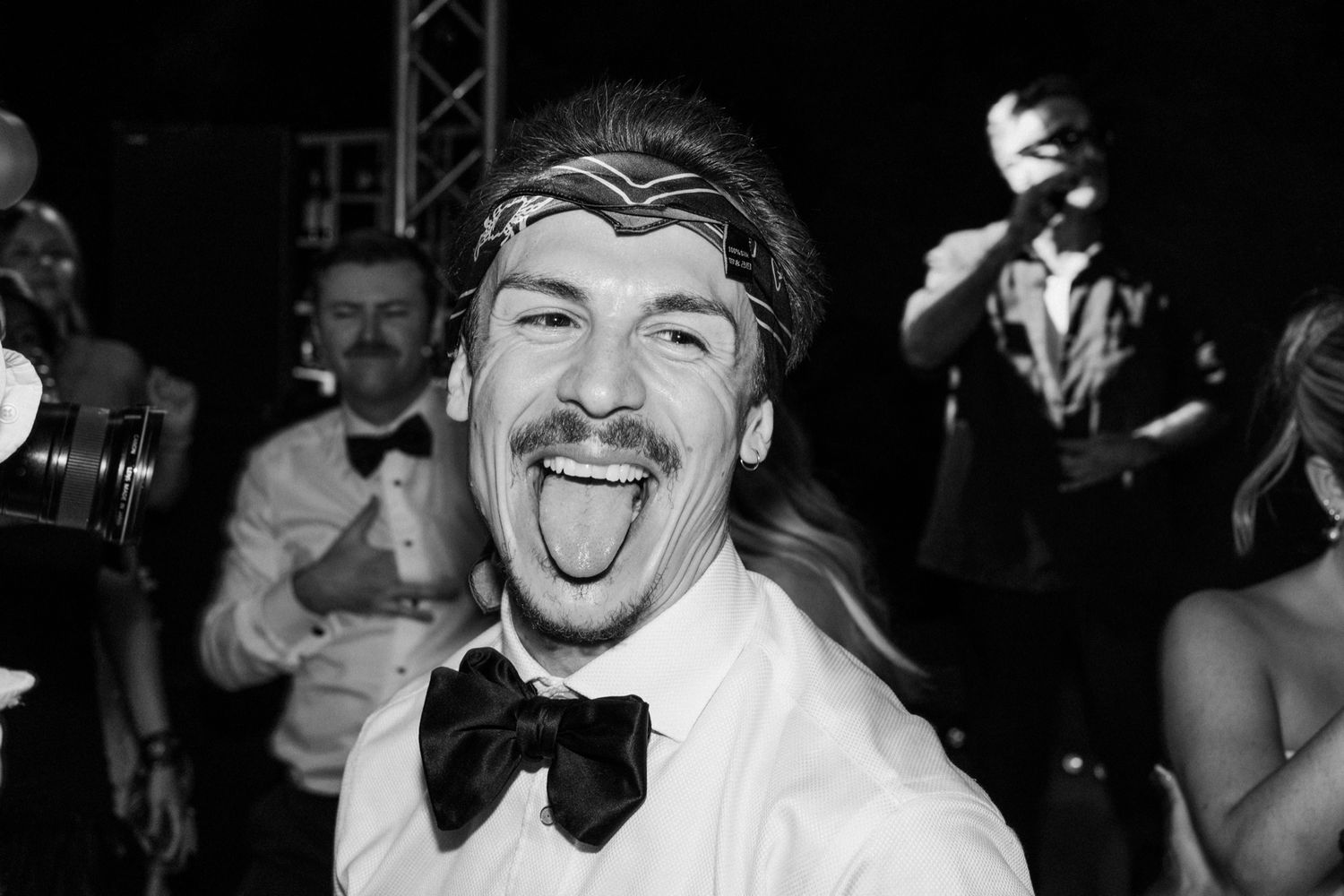 Candid black and white photo of guest in bow tie showing excitement at formal celebration.