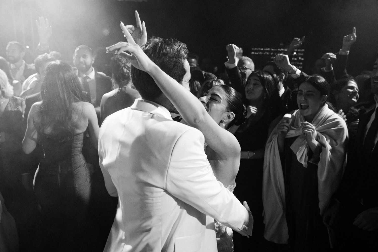 Wedding guests dance and celebrate on a crowded dance floor at an elegant reception party.