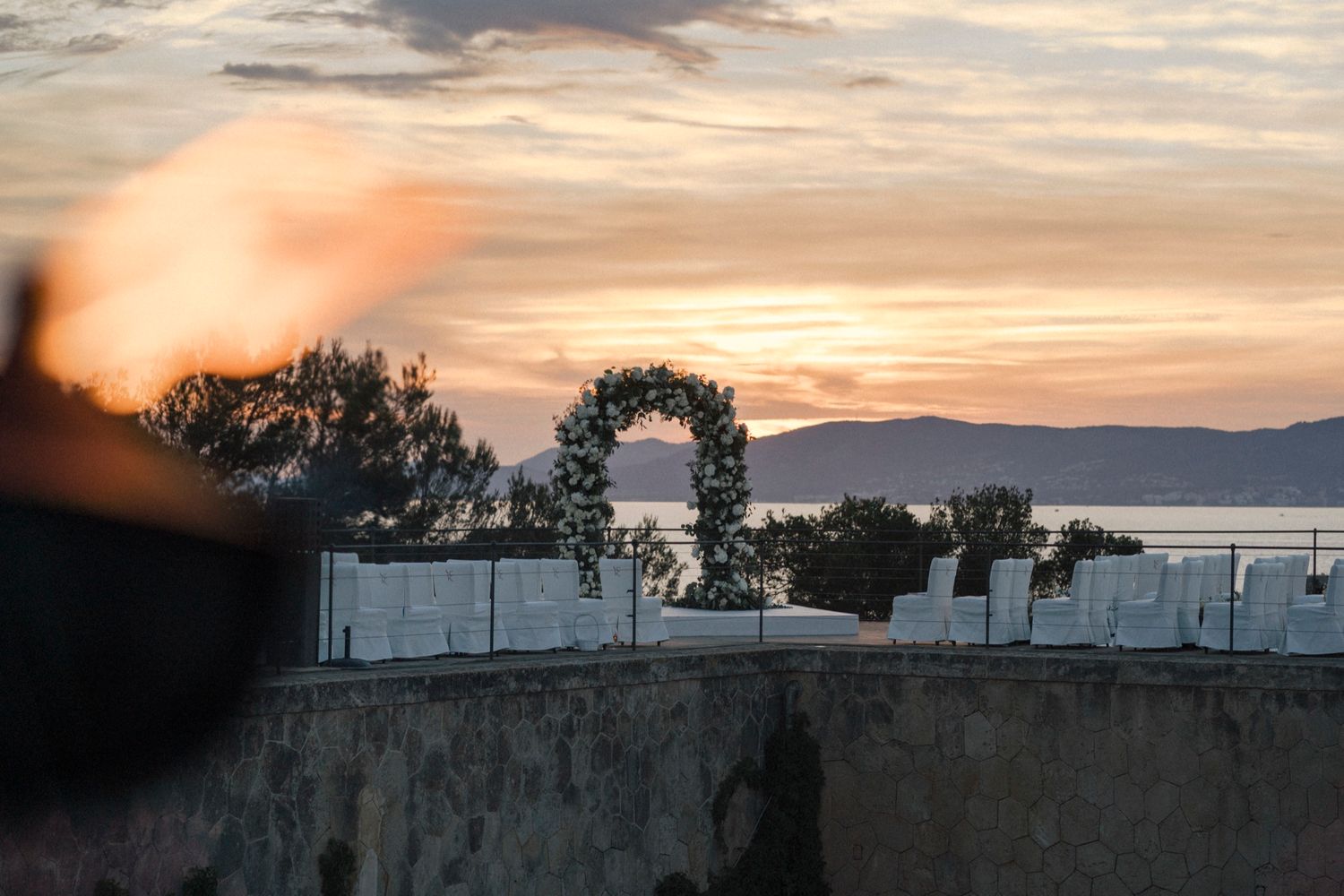 Floral arch at sunset overlooking a serene coastal landscape.