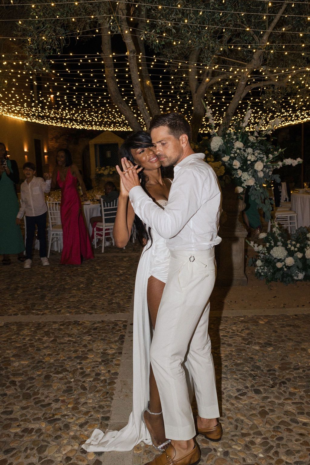 A couple shares an intimate dance moment under a canopy of twinkling lights at their reception.