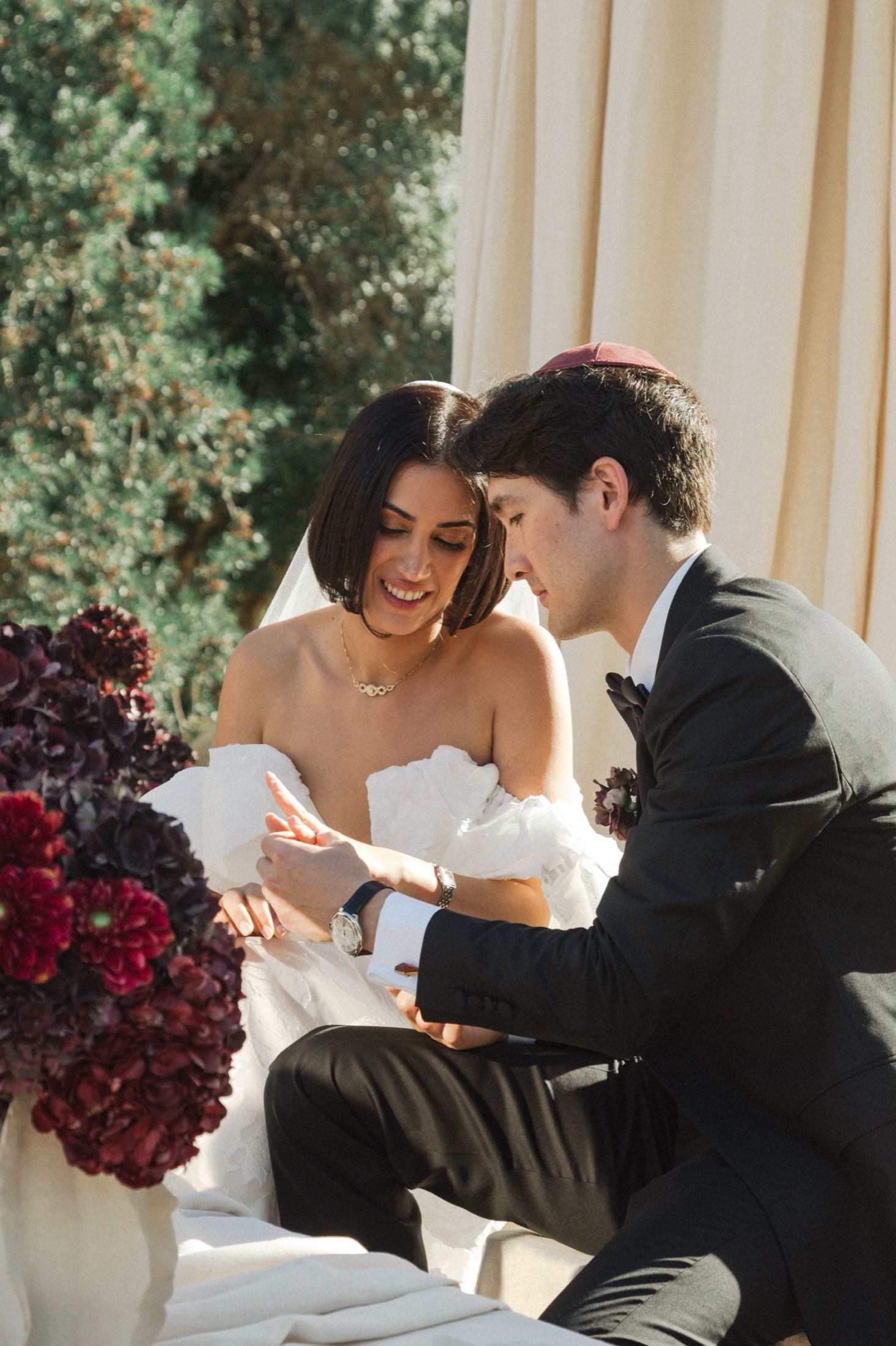 Romantic wedding couple shares intimate moments in a series of candid photos with burgundy floral arrangements.