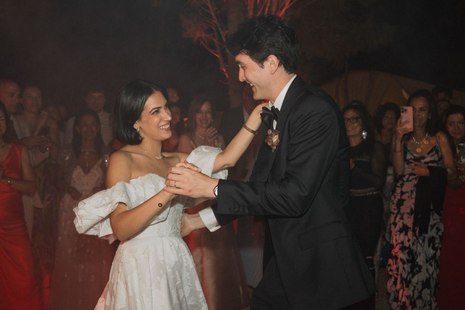 Couples dance together at a dimly lit formal event with romantic lighting and festive atmosphere.