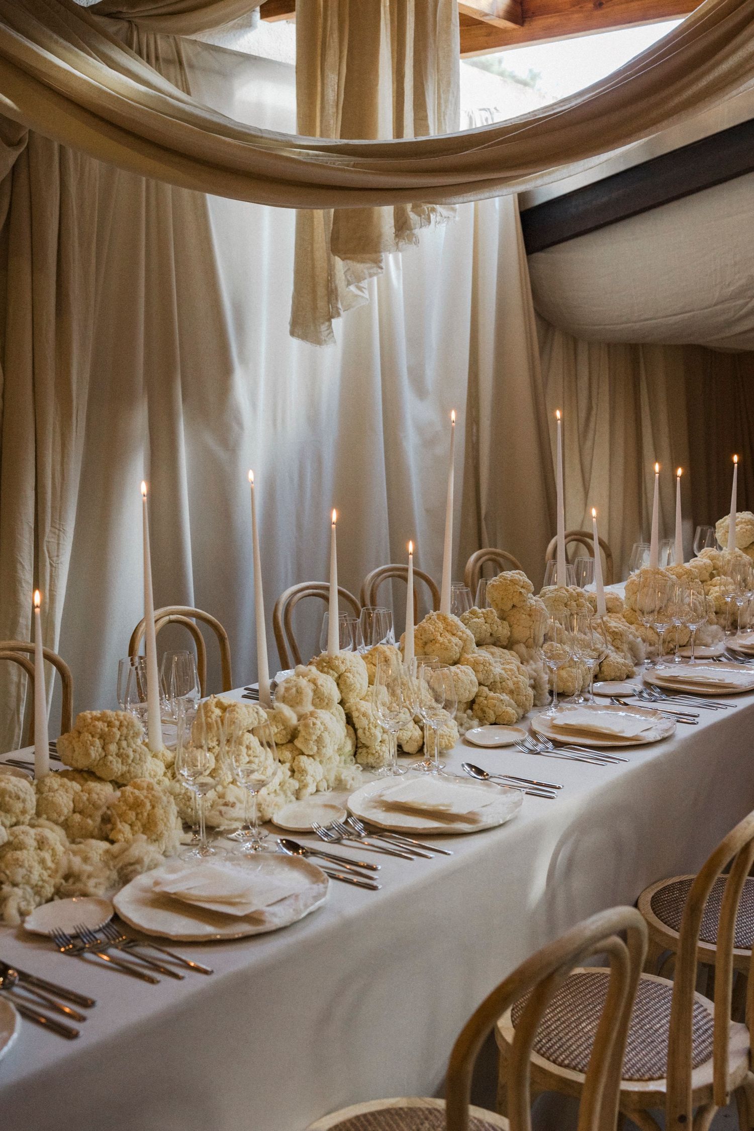 Elegant wedding reception setup with white flowers, gold chairs, and dramatic ceiling draping.
