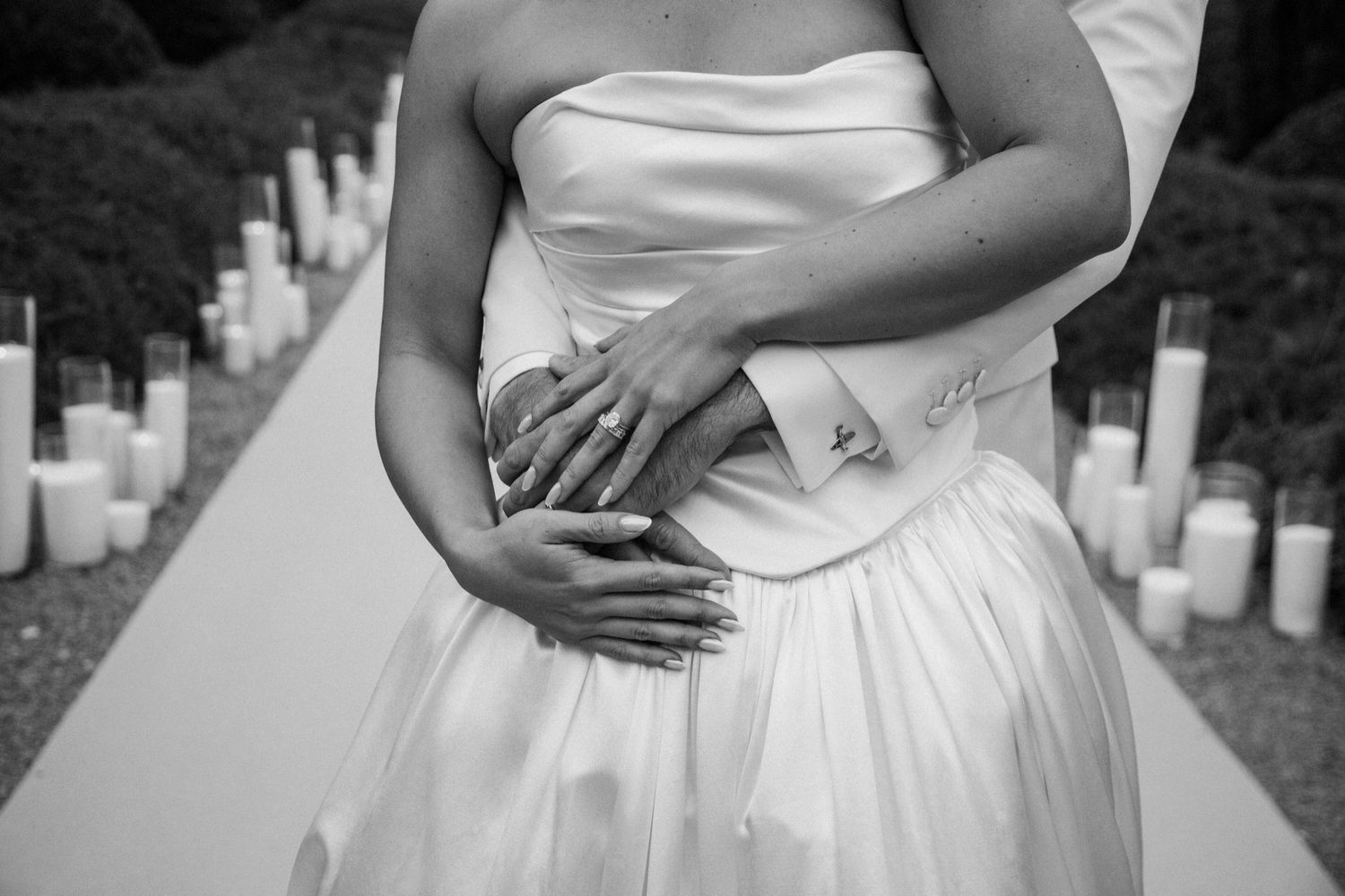 A black and white photo collage showing close-up details of a wedding dress and hands embracing.