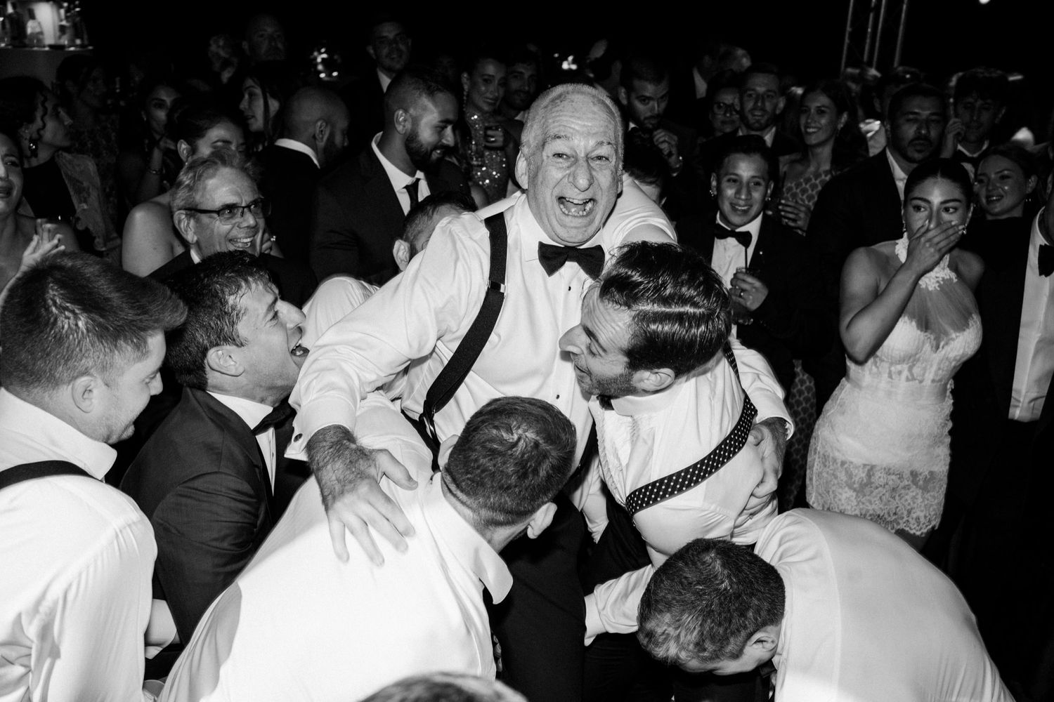 Black and white photo of people dancing and celebrating at a lively party event.