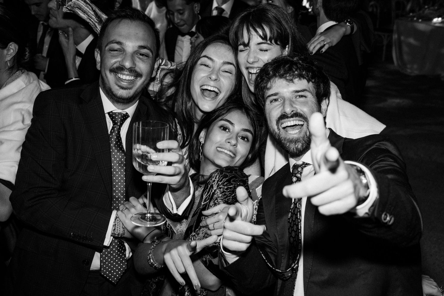 A black and white photo of a group of friends celebrating with drinks and laughter at a party.