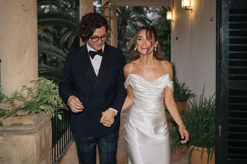 Wedding couple walking and laughing together on a covered porch.