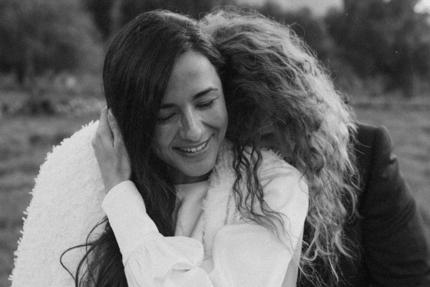 An intimate black and white portrait capturing a tender embrace outdoors.