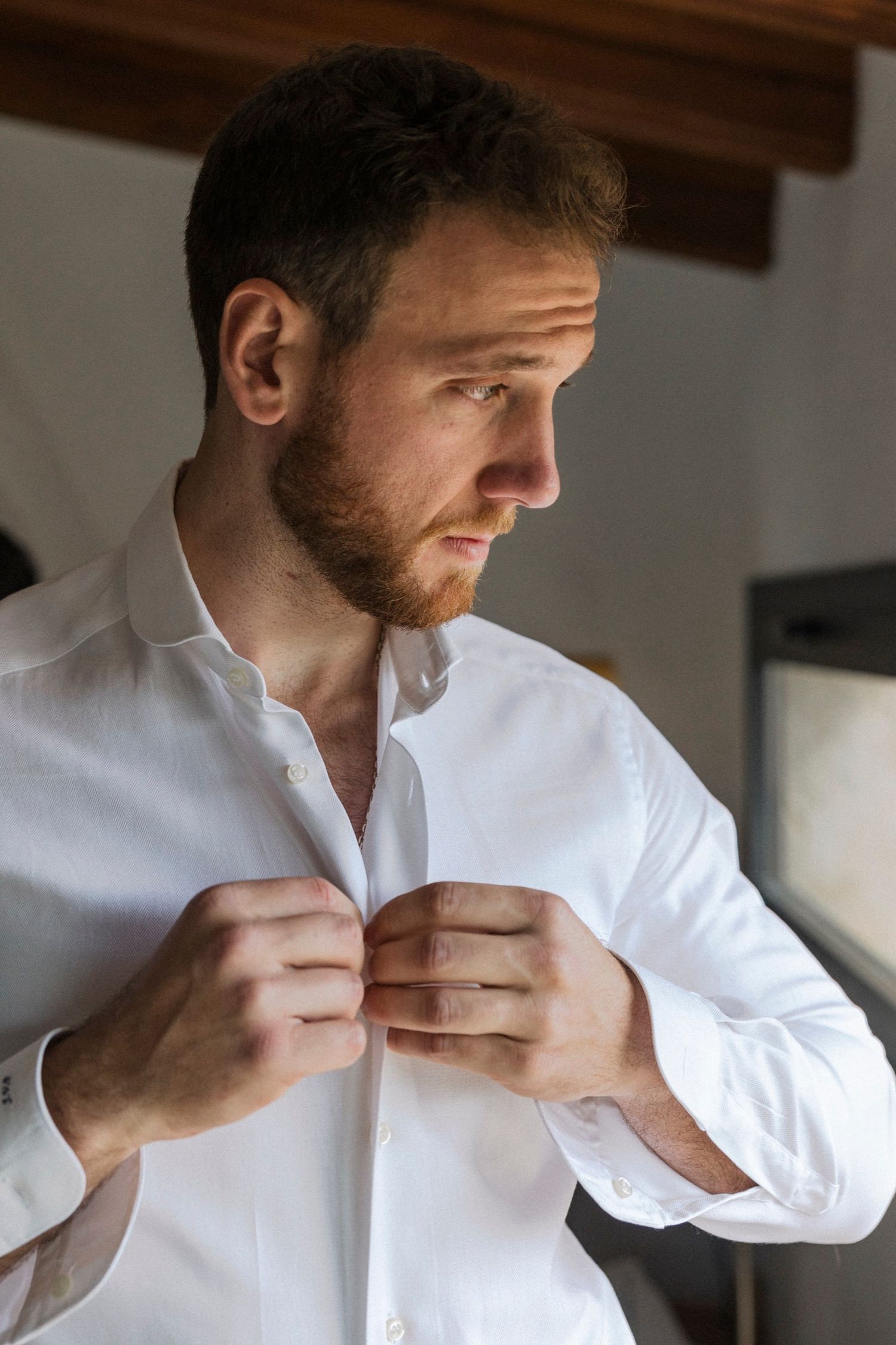 Close-up sequence showing someone buttoning up a crisp white dress shirt in multiple steps.
