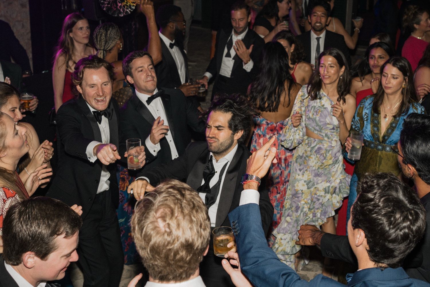 Wedding guests dancing and celebrating on a crowded dance floor at an elegant evening reception.