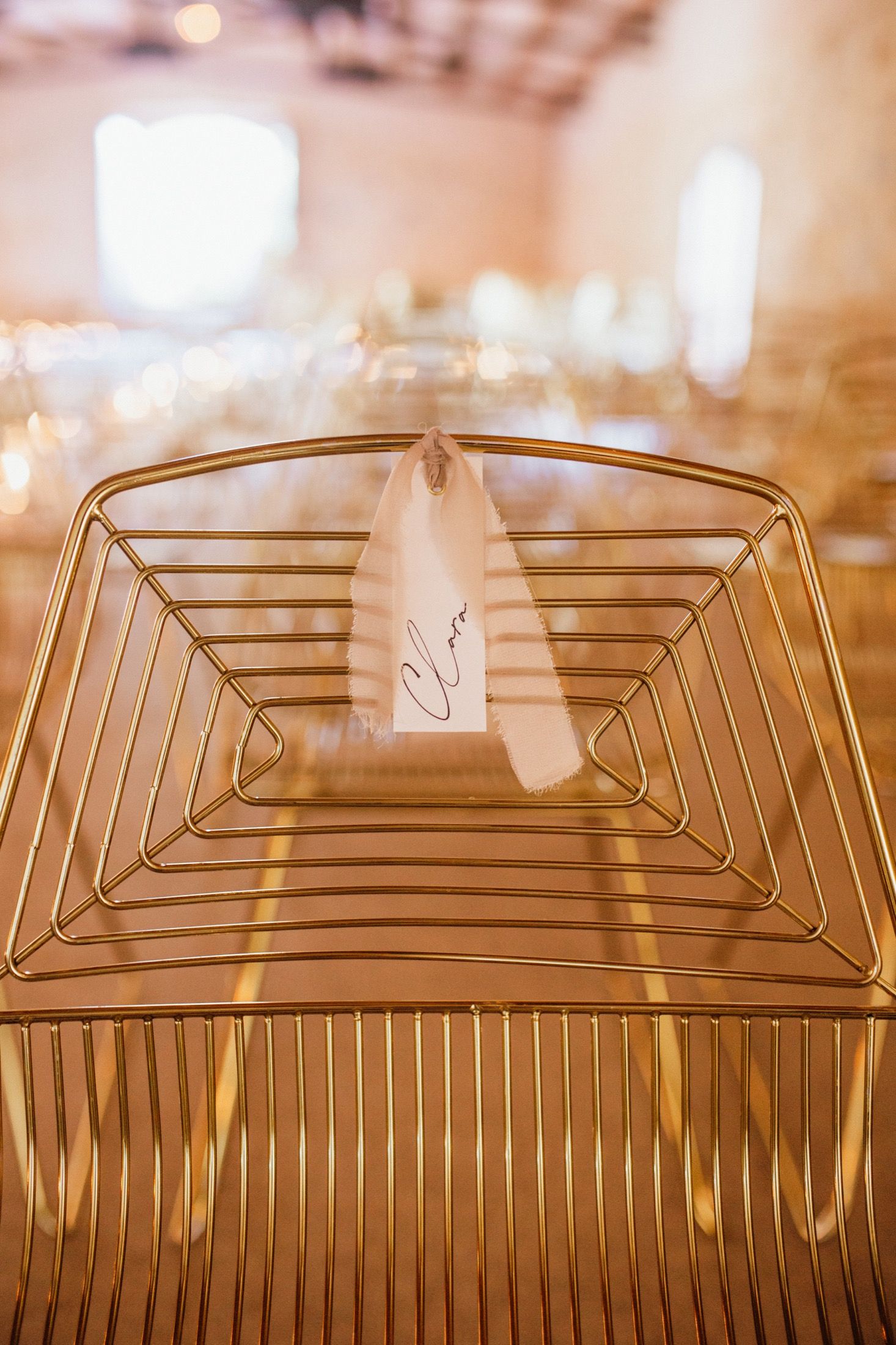 Close-up view of gold wire coat hangers arranged in a row with soft bokeh lighting in the background.