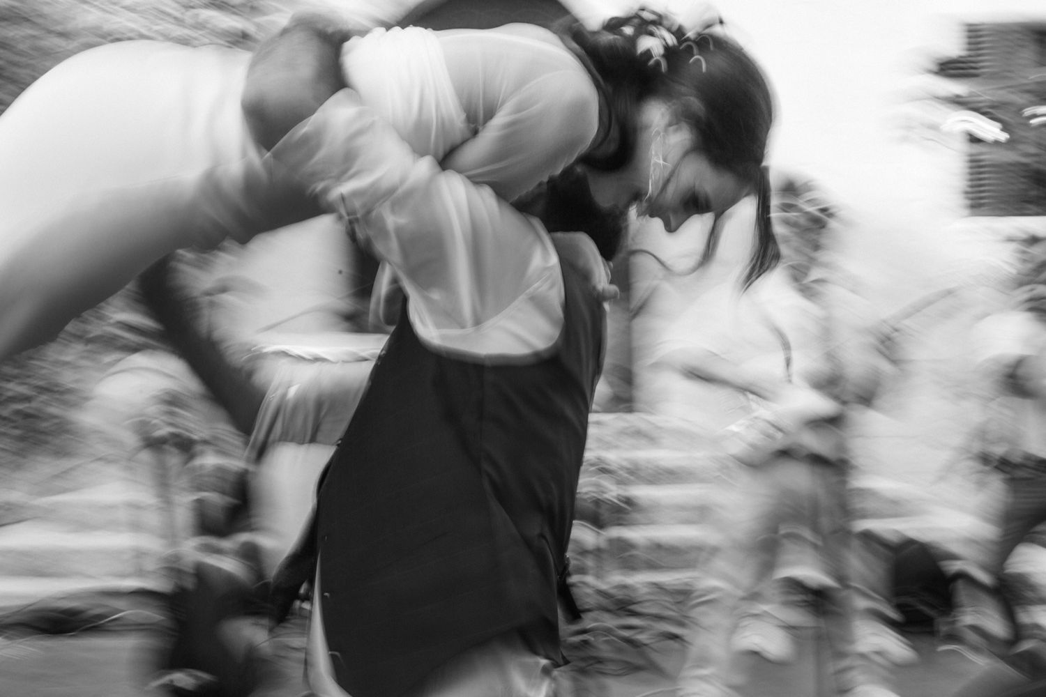 Black and white motion blur photograph of dancers in formal attire performing on a dance floor.
