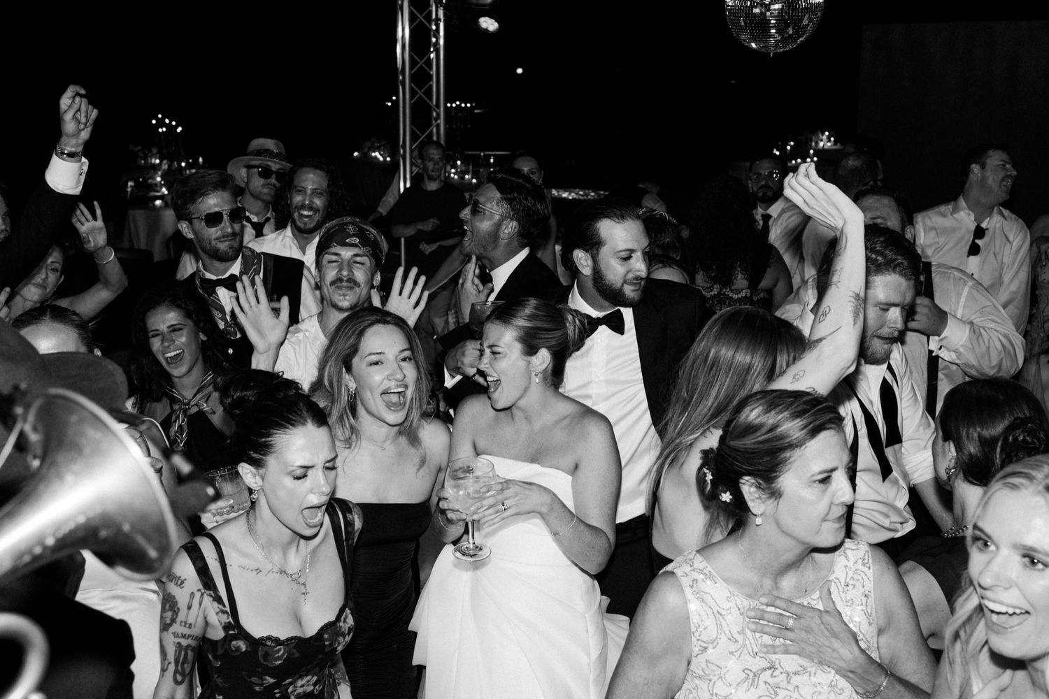 Black and white photo of energetic wedding reception dance floor filled with celebrating guests.