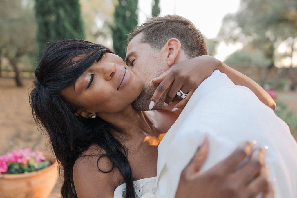 Romantic wedding couple sharing intimate moments in a Mediterranean garden setting.