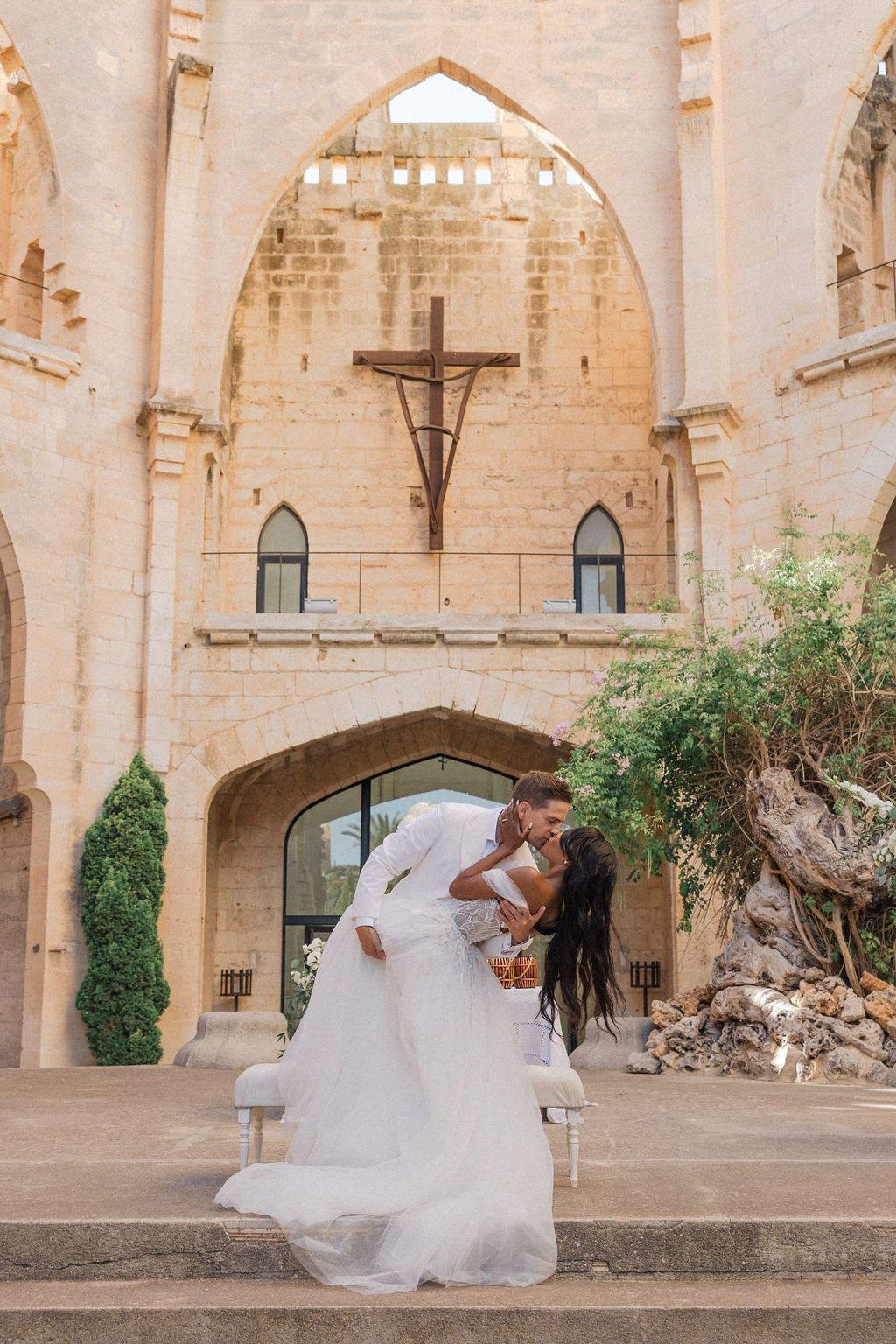 Bride dances joyfully in flowing gown against backdrop of ancient stone architecture.