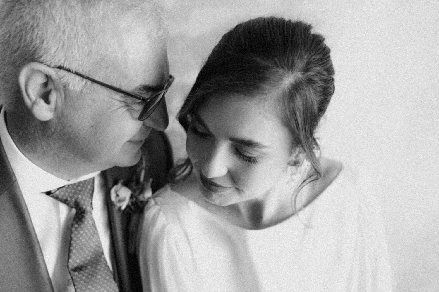 A tender black and white portrait of an intimate moment between two people at a formal event.