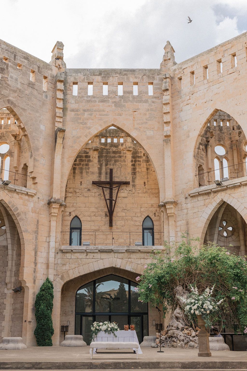 Medieval stone courtyard with Gothic arches and modern glass windows prepared for an event.