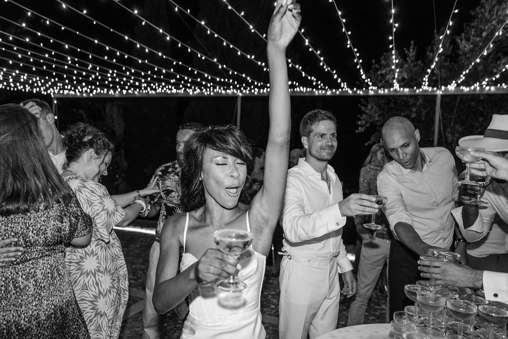 Wedding guests celebrate under string lights at an outdoor reception.