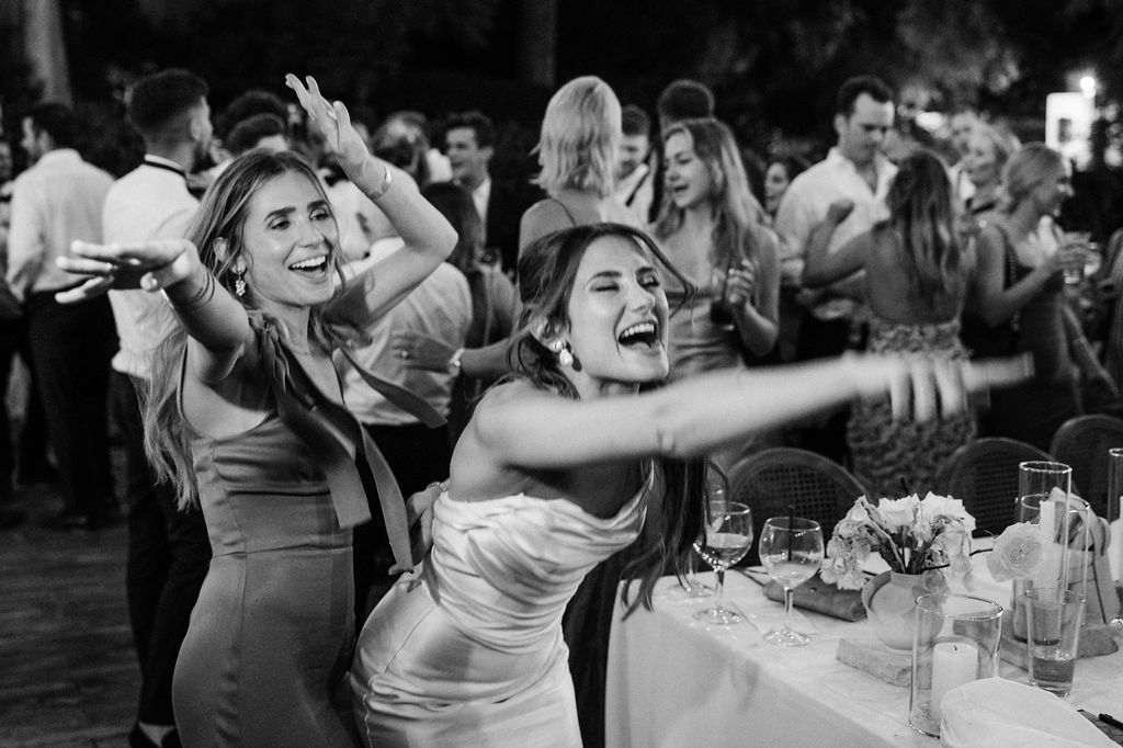 Black and white photo of guests laughing and celebrating at a wedding reception.