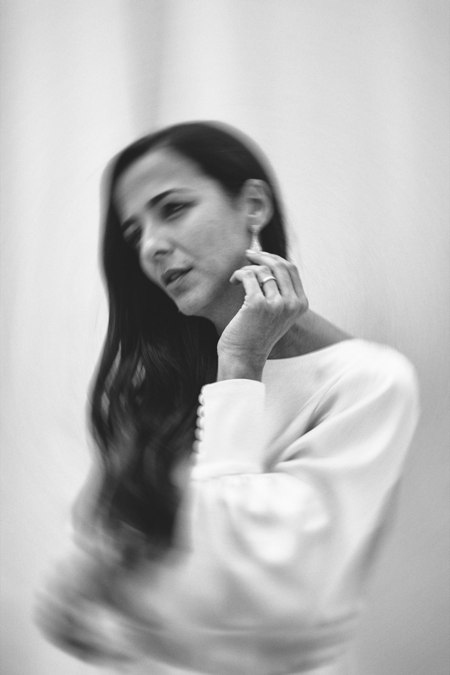An artistic black and white portrait showing someone in white displaying an engagement ring.