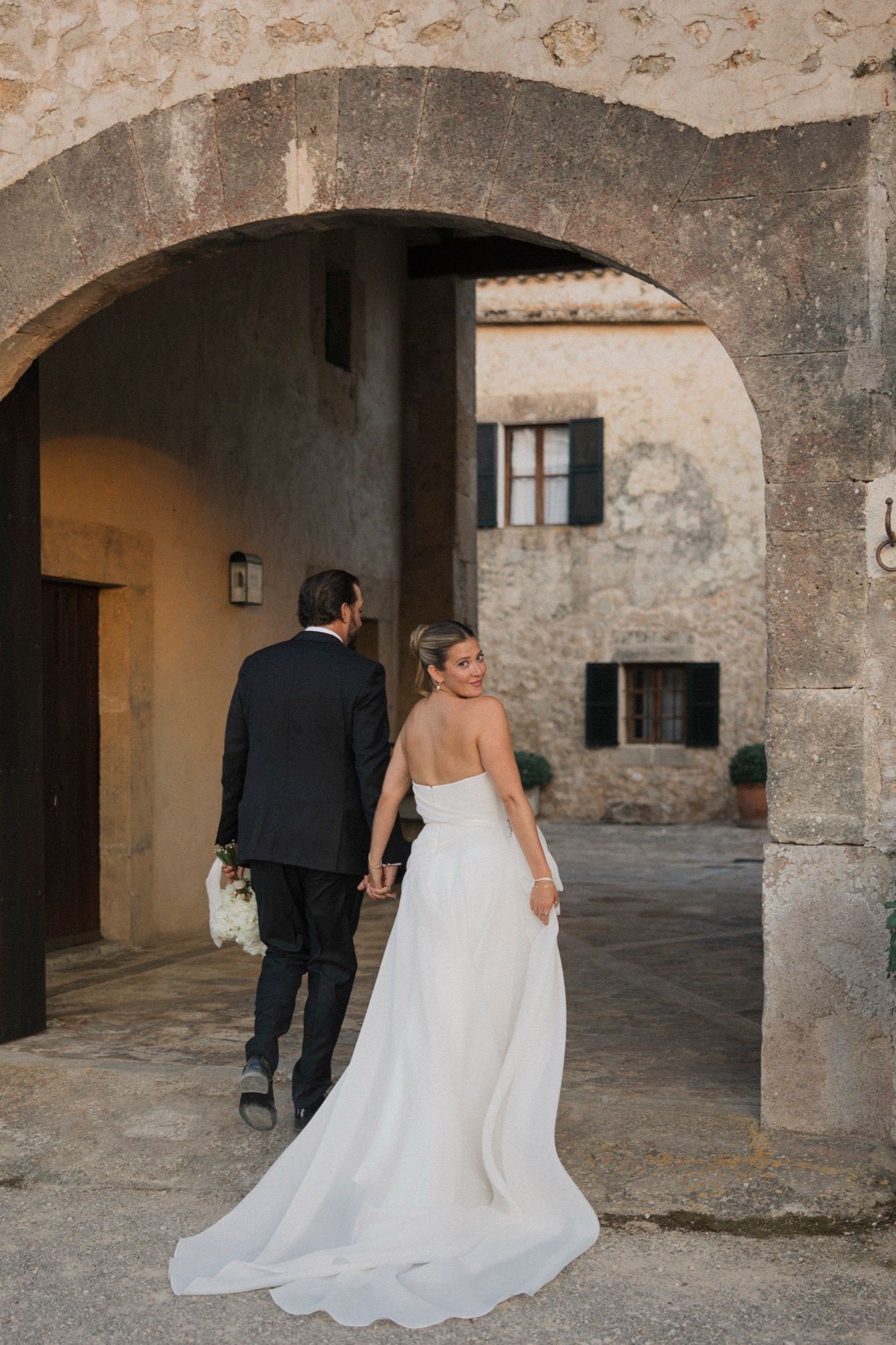 Wedding couple walking through historic stone archways and corridors.