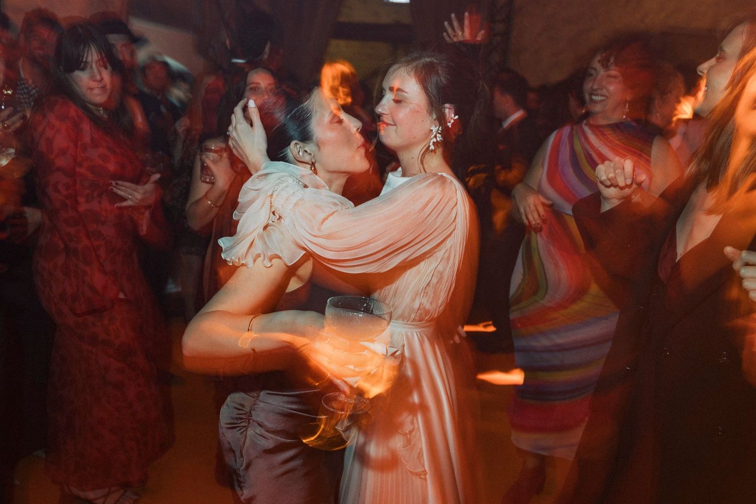 Couples dance together in a dimly lit ballroom with warm orange lighting creating a romantic atmosphere.