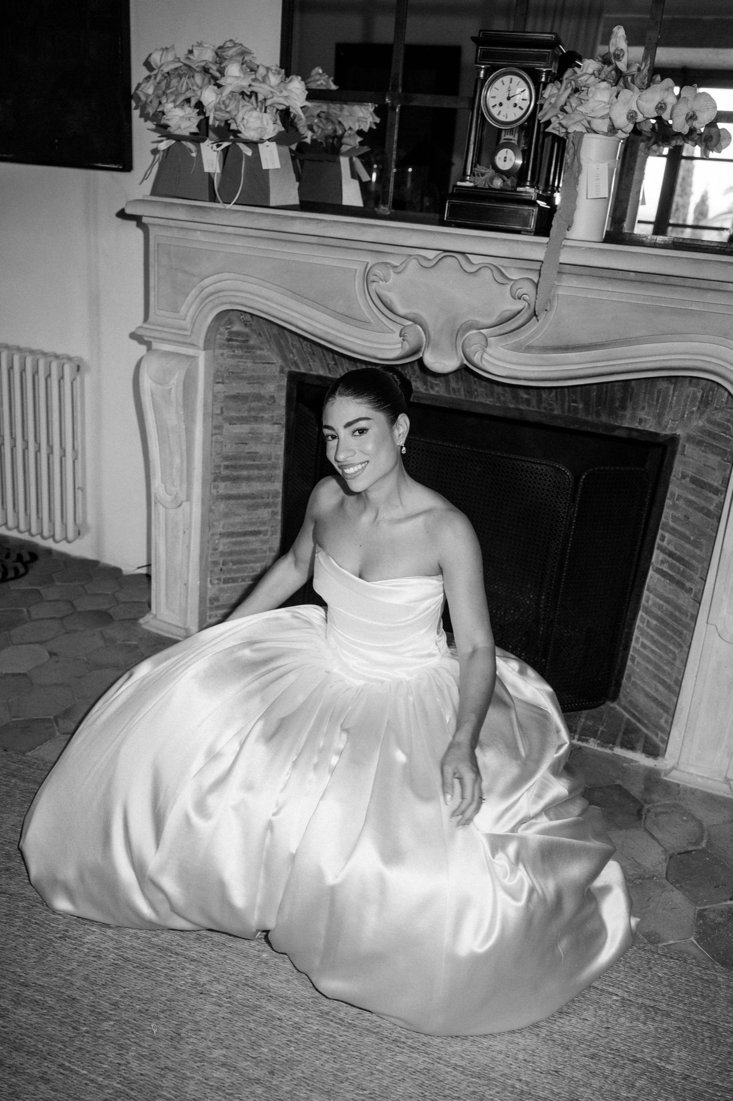 A series of black and white photographs showing a person in an elegant white strapless gown sitting on the floor near a fireplace.