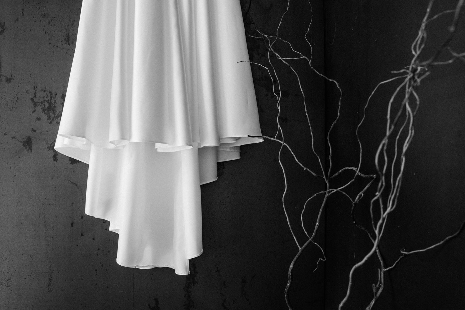 A series of black and white photographs showing white dresses or garments hanging against dark backgrounds.