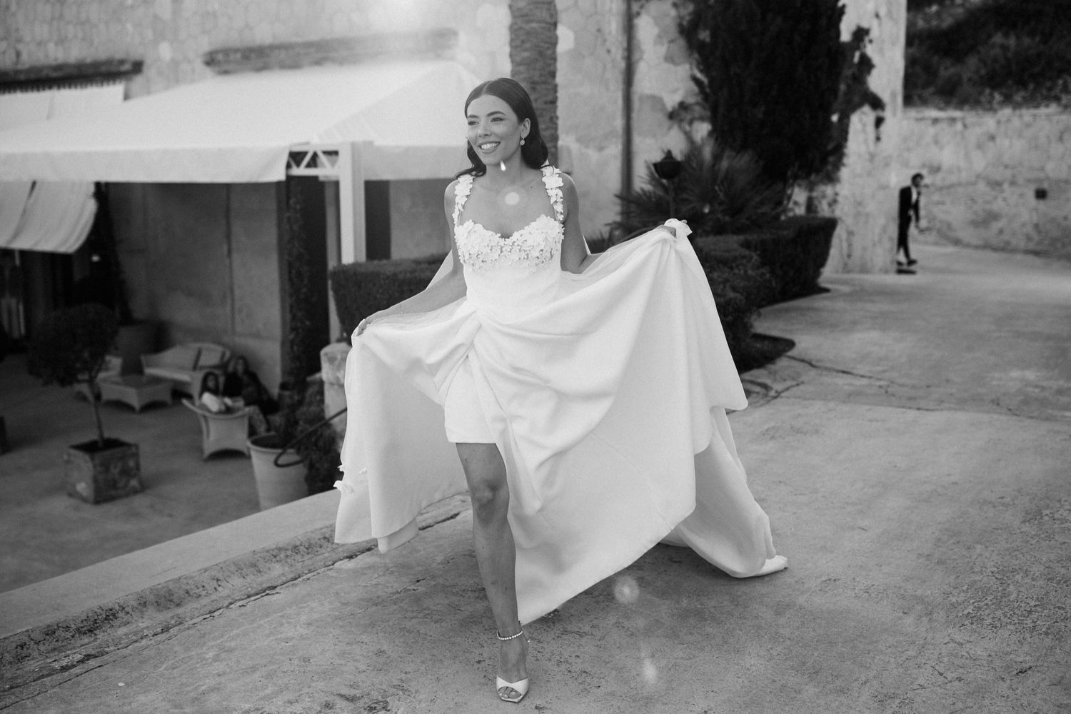 Bride in white wedding dress twirling outdoors in black and white photo.