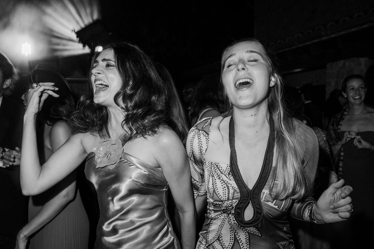 A group of people dancing and laughing together at a lively party in a dimly lit venue.