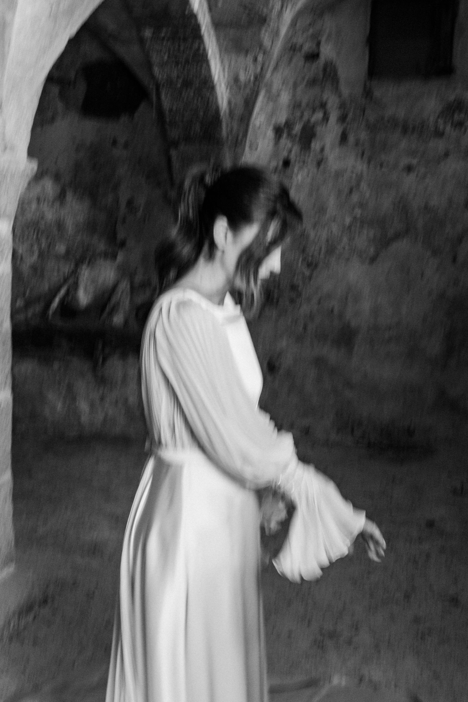 A series of four black and white photos showing someone in a white dress walking and spinning outdoors.