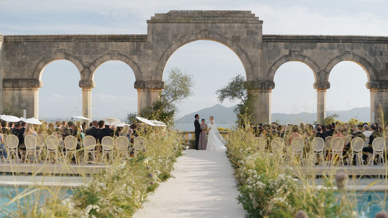 Ancient stone ruins of Volubilis, a Roman archaeological site in Morocco, with arched columns against a cloudy sky.