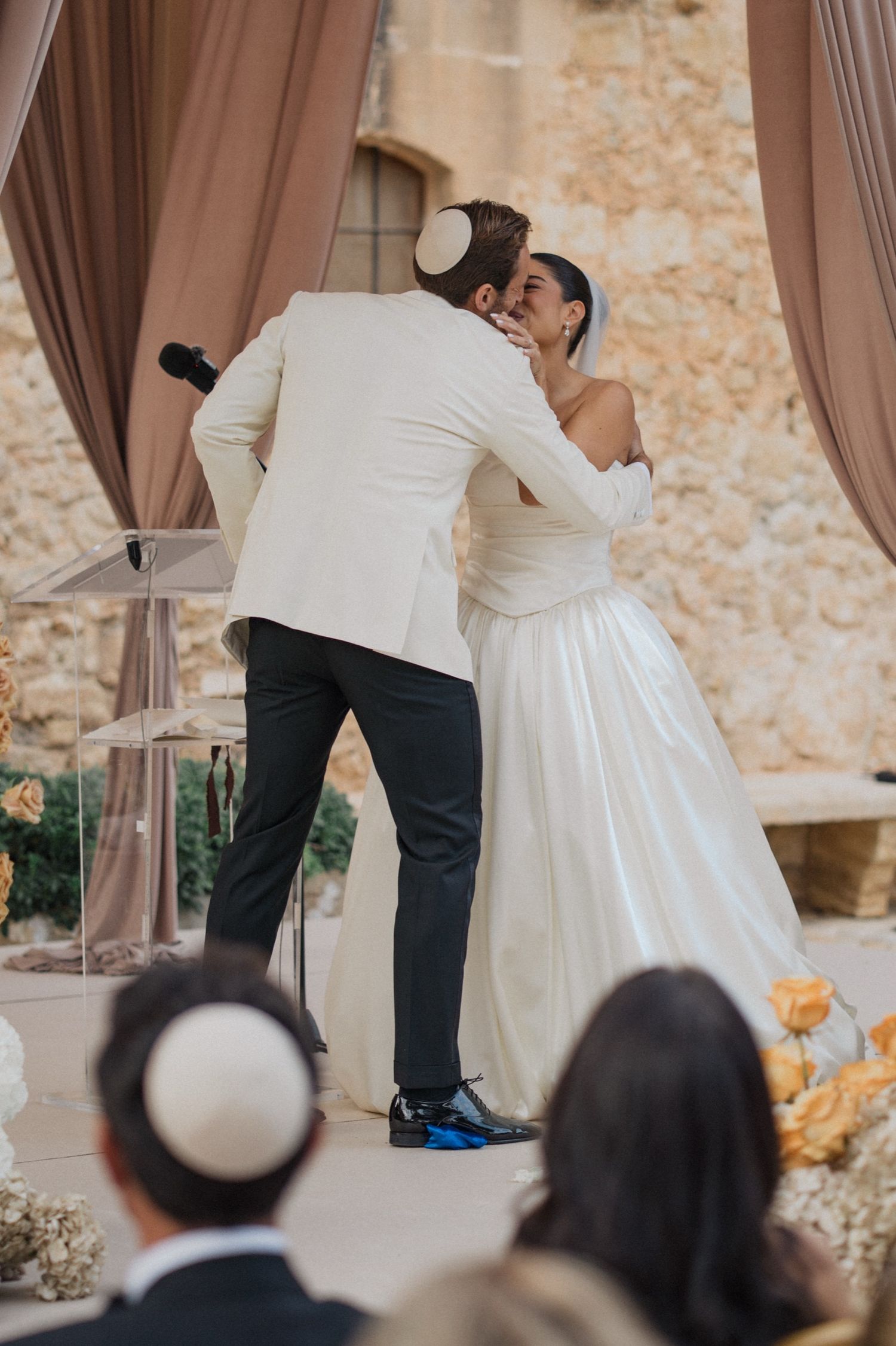 A couple performs a romantic dance lift during a wedding celebration while guests watch from their seats.