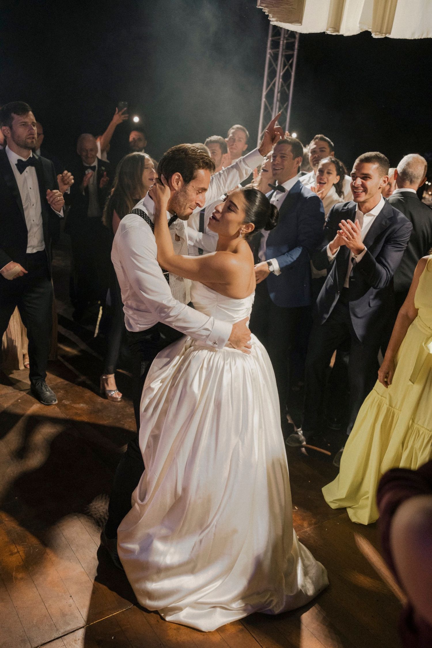 A couple shares their first dance at their wedding reception while guests watch and celebrate on the dance floor.