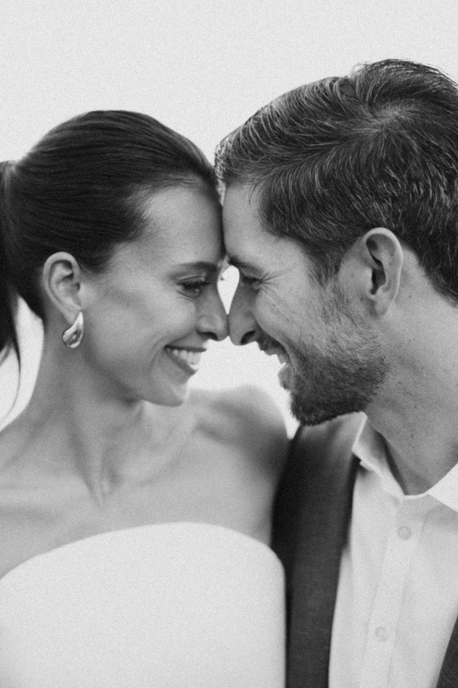 A black and white image of a smiling couple gazing lovingly at each other.