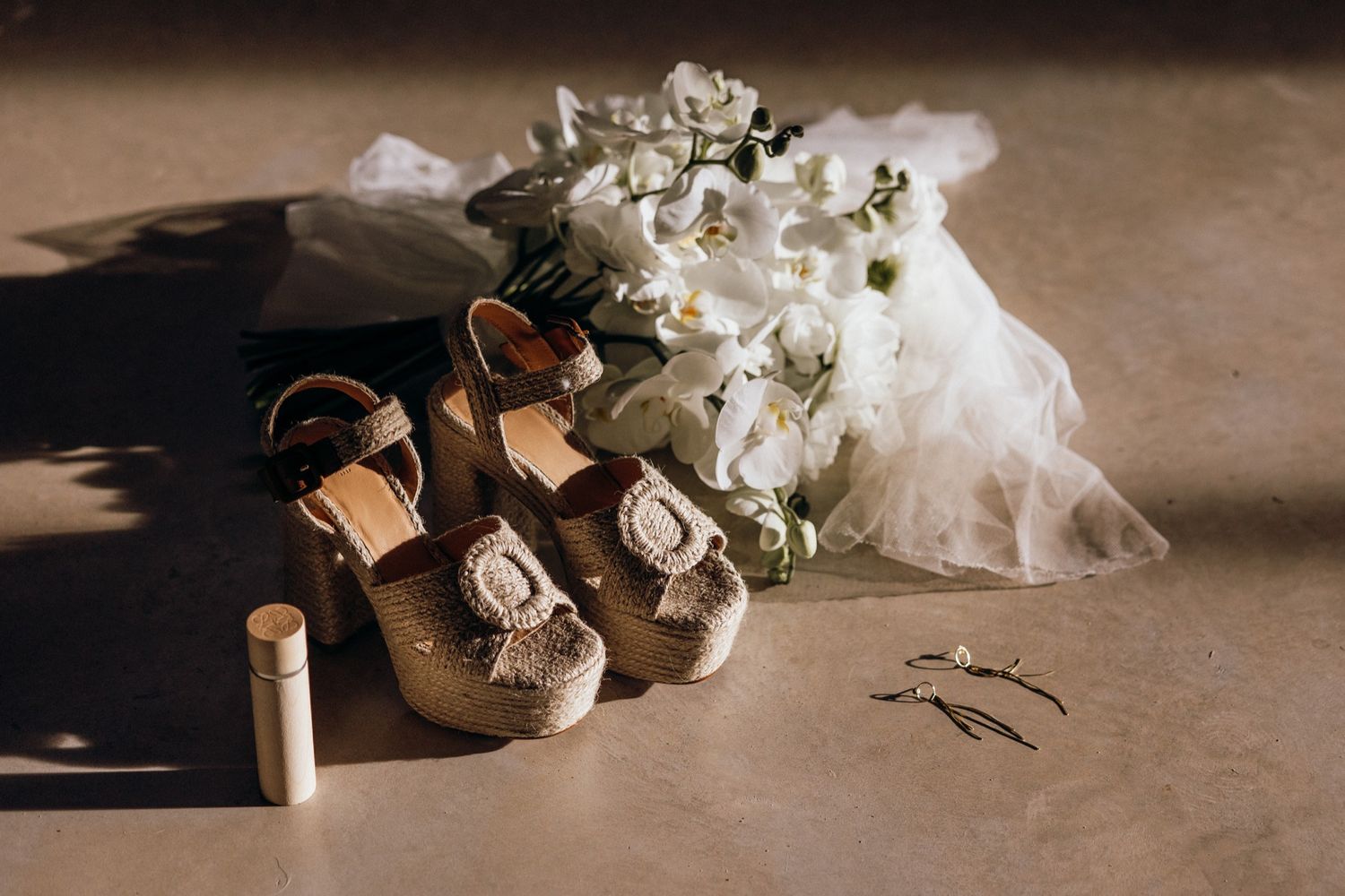 Elegant wedding details including white floral arrangements, invitations and delicate decor elements in warm moody lighting.