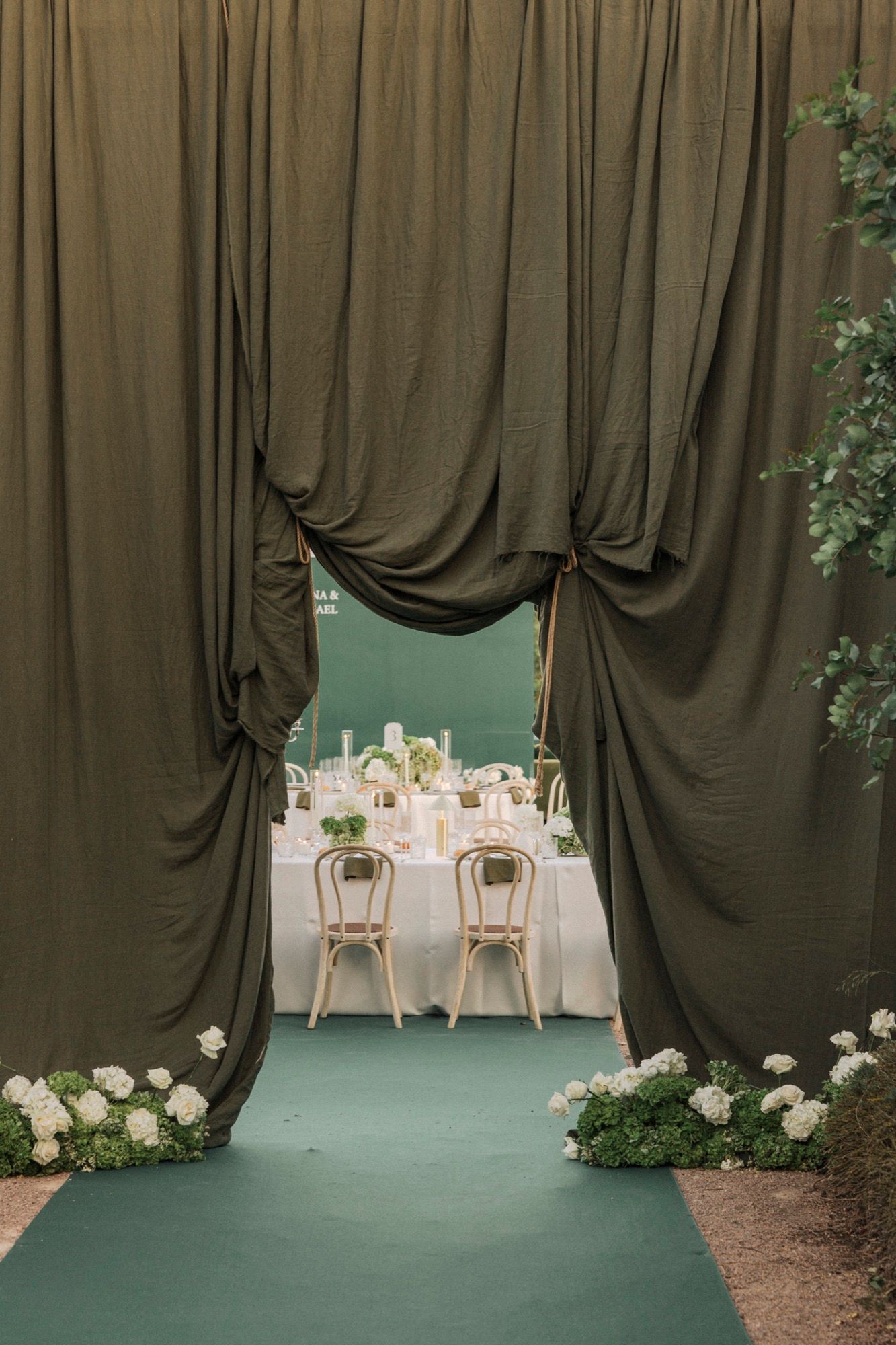 Elegant wedding reception setup with dramatic dark drapes and white table settings.