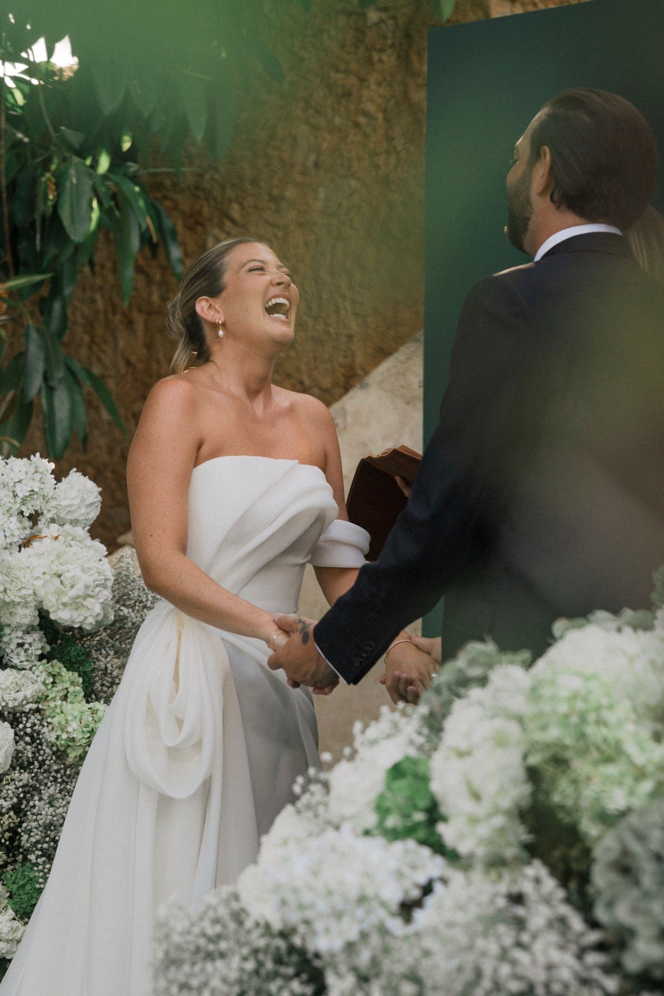 Joyful wedding ceremony moment surrounded by white floral arrangements and greenery.
