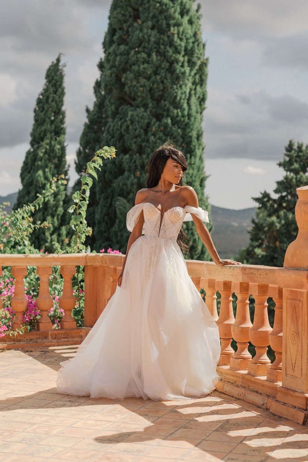 Sunlit stone terrace with ornate balustrades overlooking a Mediterranean landscape.