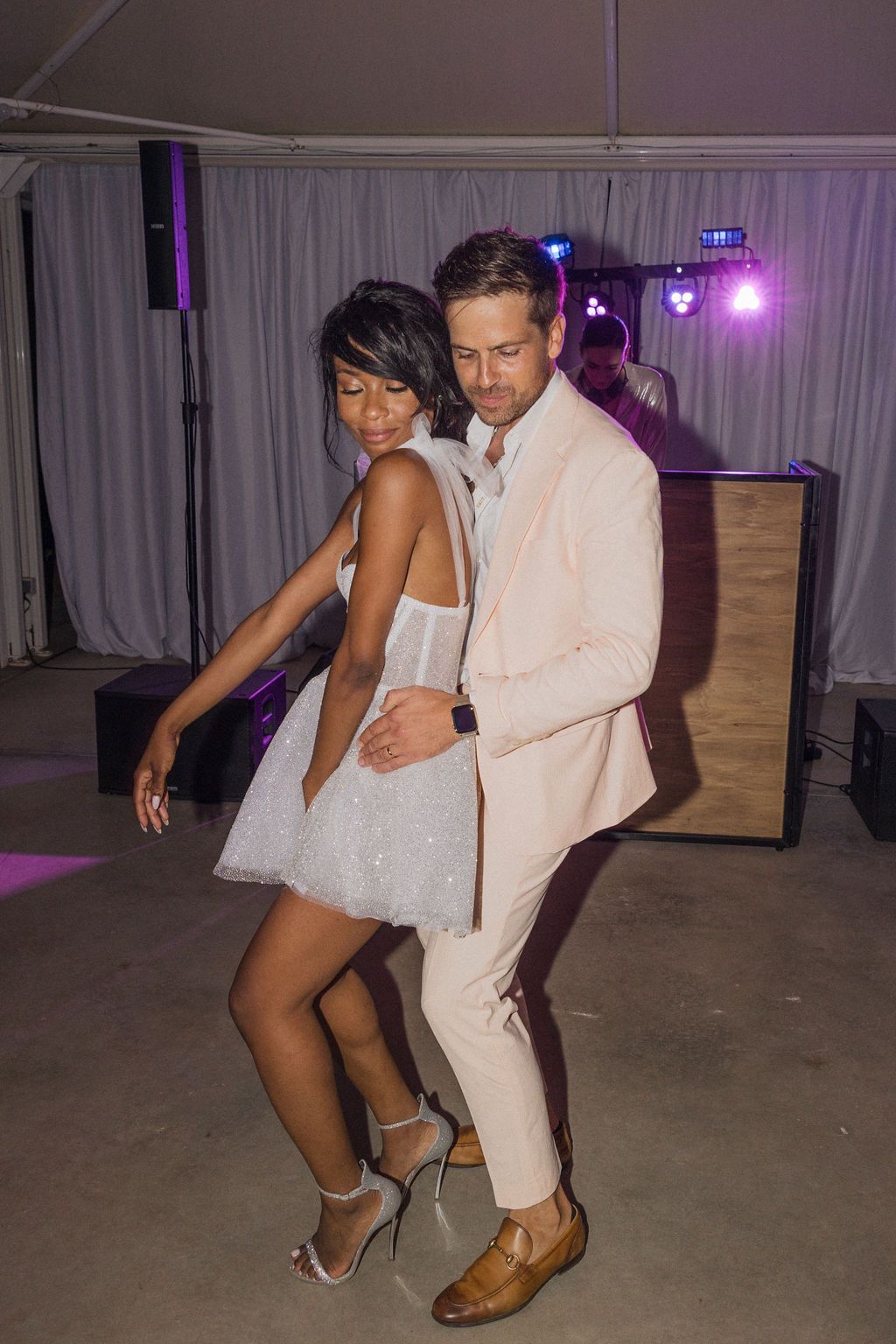 A couple performs a dynamic dance routine on a wooden floor with purple ambient lighting.